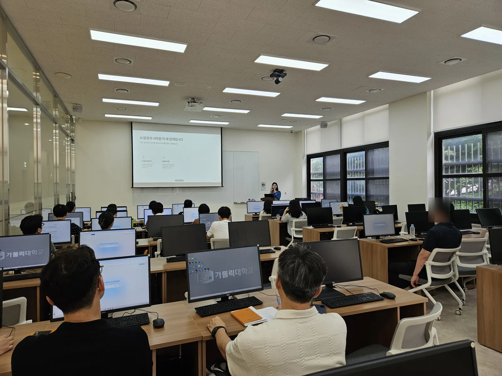 가톨릭대학교 전산실에서 교직원들이 'AI 활용의 시작은 이 네 단계입니다' 슬라이드를 보는 모습